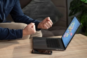 Man with clenched fists at laptop on table