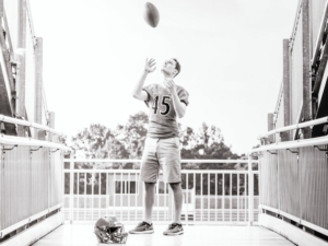 Grayscale photo of Football player tossing football in air