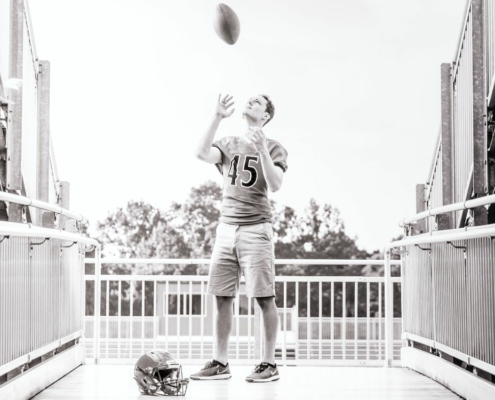 Grayscale photo of Football player tossing football in air